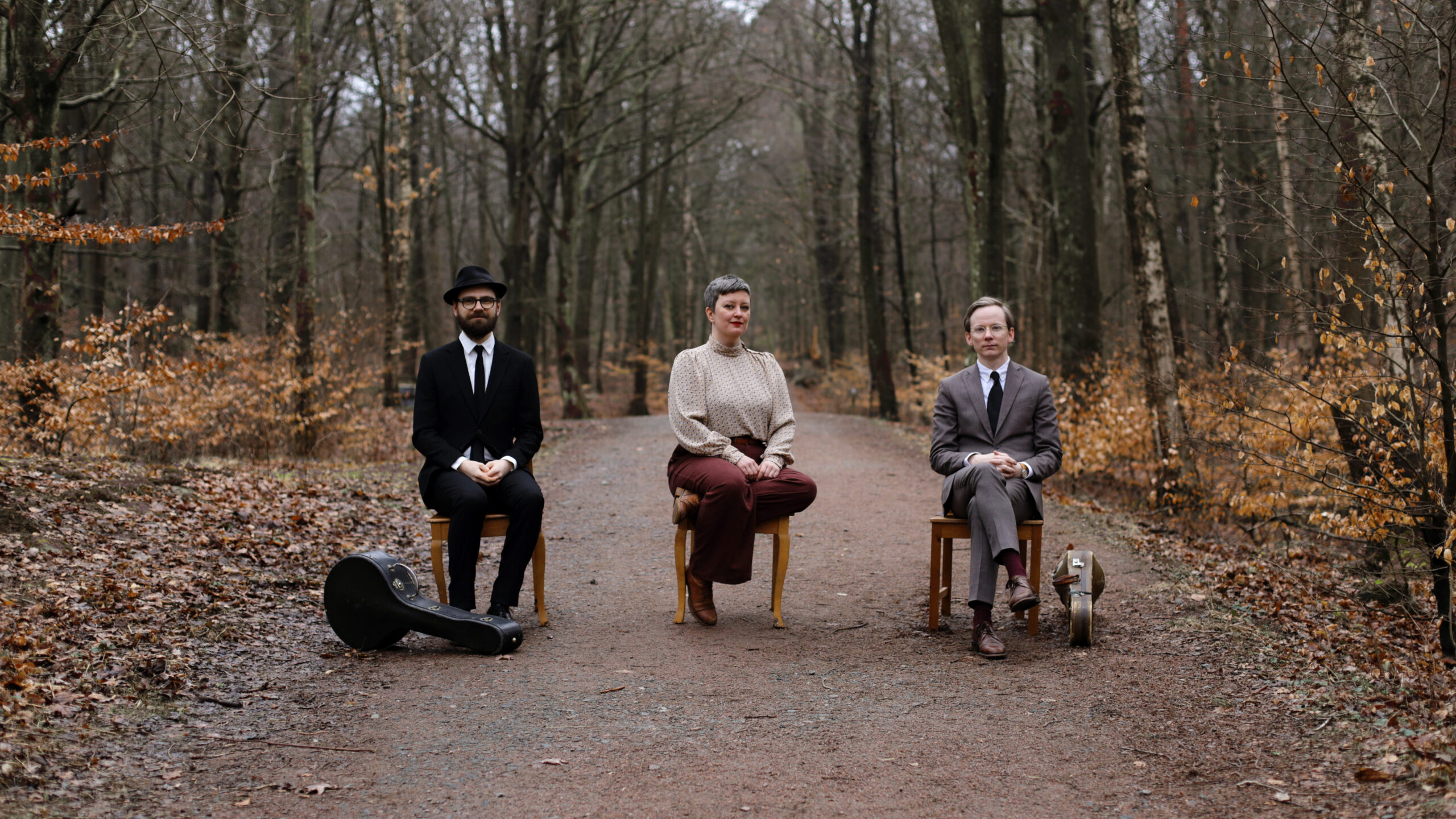The Sky is Crying sitting on chairs on a dirt road in the forest